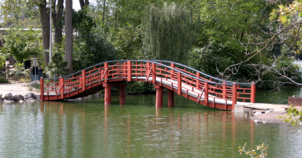 Red arched Japanese-style bridge over a tranquil pond at Rotary Botanical Gardens in Janesville, Wisconsin.