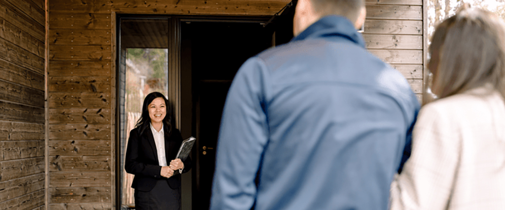 Real estate agent greeting customers at a home