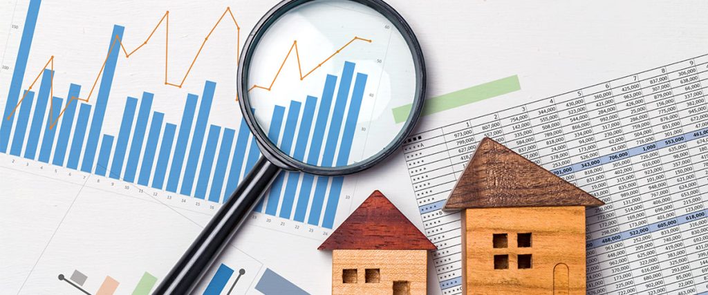 Real estate investment graph with magnifying glass and miniature house models.