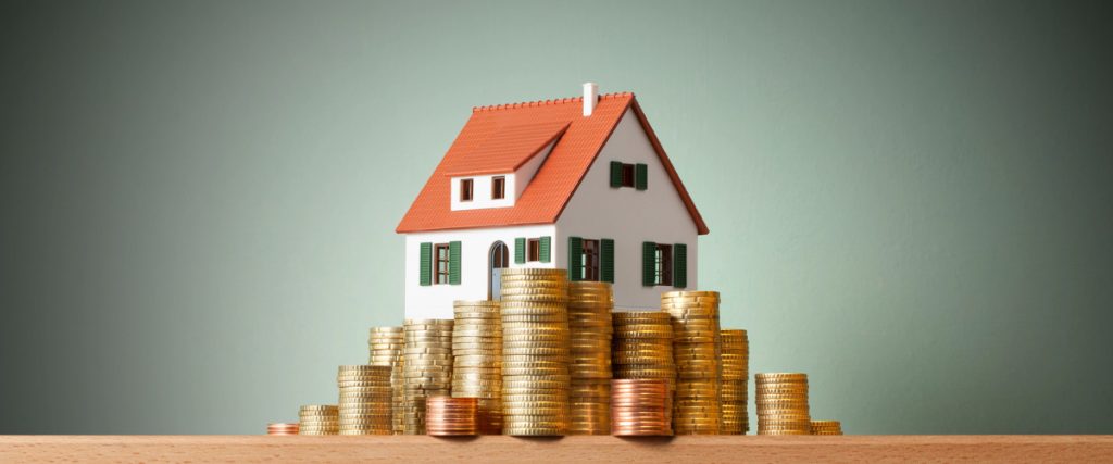 A small decorative house model surrounded by gold coins symbolizing rising home value.