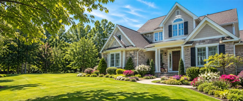May home selling curb appeal with a well-maintained home, lush green lawn, mature trees, and colorful landscaping.