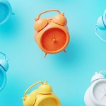 Colorful alarm clocks on a blue background representing the best time to list your house.