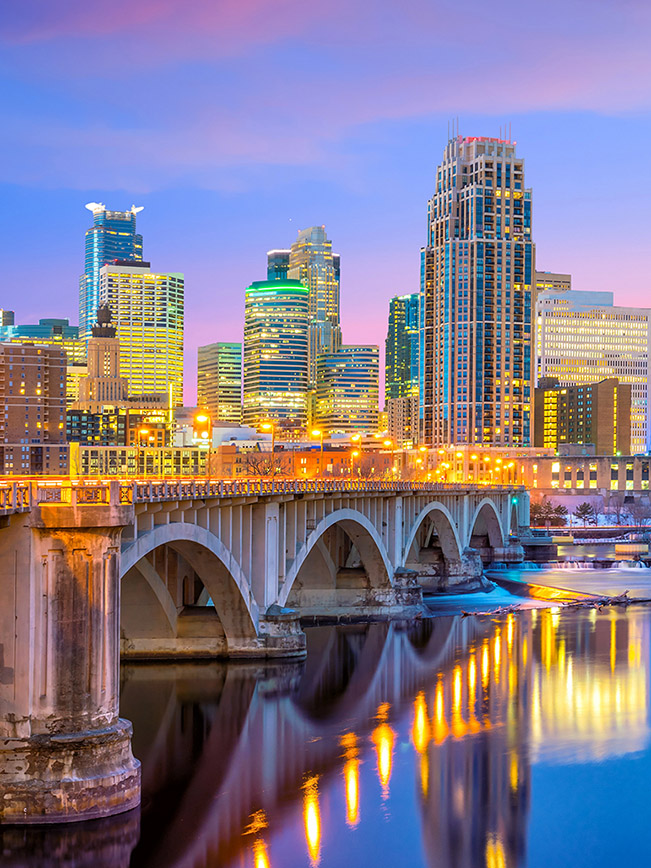 Twilight view of the vibrant downtown Minneapolis skyline and riverfront.