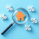 Magnifying glass over an orange house icon surrounded by percent symbols.